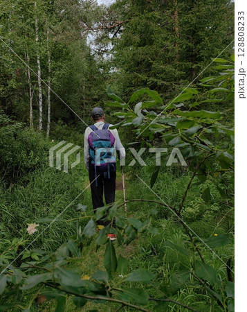 person hiking along forest trail surrounded by lush greenery during daytime. 128808233