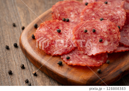 木製のカッティングボードに載せた美味しそうなサラミのスライス 128808383