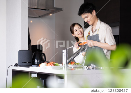 料理を作る若いカップル 料理を作る若いカップル 128808427