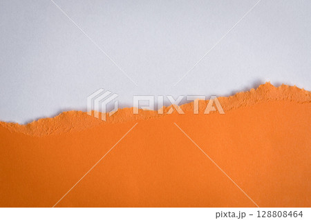 Torn orange paper on top of white color paper. 128808464