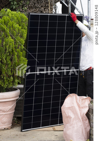 太陽光パネルを住宅の屋根に設置する工事 作業の様子 太陽光パネルを住宅の屋根に設置する工事 作業の様子 128809148