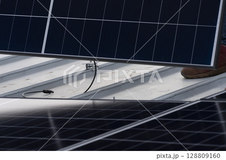 太陽光パネルを住宅の屋根に設置する工事　作業の様子 128809160