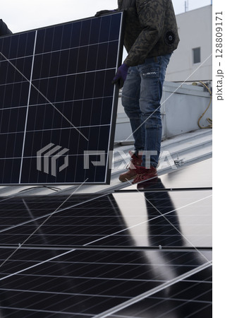 太陽光パネルを住宅の屋根に設置する工事 作業の様子 太陽光パネルを住宅の屋根に設置する工事 作業の様子 128809171