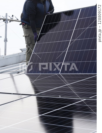 太陽光パネルを住宅の屋根に設置する工事　作業の様子 128809172