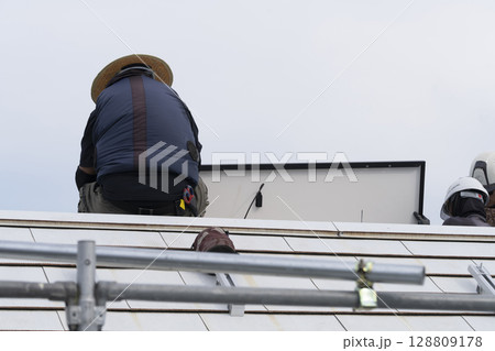 太陽光パネルを住宅の屋根に設置する工事 作業の様子 太陽光パネルを住宅の屋根に設置する工事 作業の様子 128809178