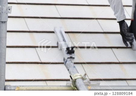 太陽光パネルを住宅の屋根に設置する工事　作業の様子 128809184