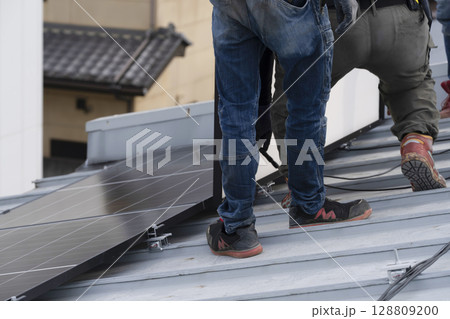 太陽光パネルを住宅の屋根に設置する工事　作業の様子 128809200