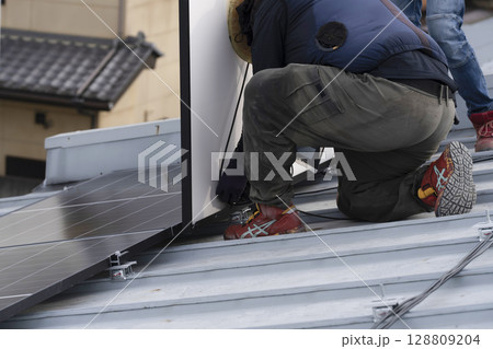 太陽光パネルを住宅の屋根に設置する工事　作業の様子 128809204