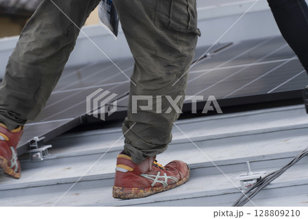 太陽光パネルを住宅の屋根に設置する工事　作業の様子 128809210