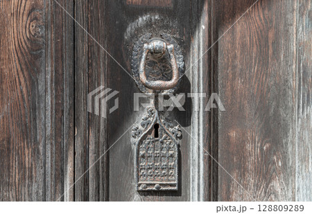 Aged wooden door with Ornamental keyhole and knocker, Antique wooden gate of Holy trinity church. Aged wooden door with Ornamental keyhole and knocker, Antique wooden gate of Holy trinity church. 128809289