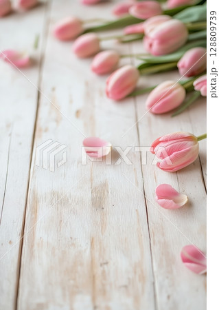 Pink tulips and petals beautifully arranged on a rustic wooden table 128809739