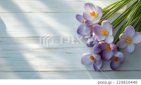 Fresh purple crocuses on a light wooden surface with soft shadows 128810446