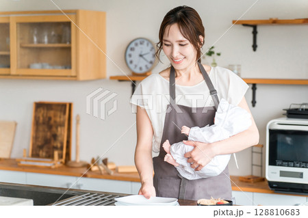 キッチンで赤ちゃんを抱っこする若いアジア人女性 128810683