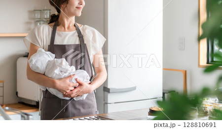 キッチンで赤ちゃんを抱っこする若いアジア人女性 128810691