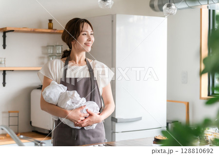 キッチンで赤ちゃんを抱っこする若いアジア人女性 128810692