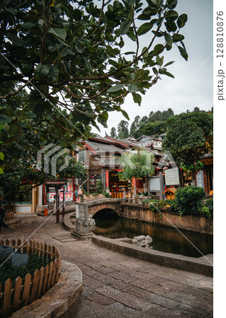 Serene canal view in Lijiang Old Town with trees and stone paths 128810876