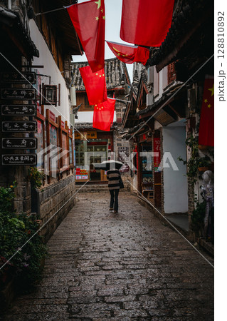 Tourists walking under umbrellas in Lijiang Old Town shopping street Tourists walking under umbrellas in Lijiang Old Town shopping street 128810892