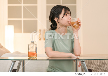 家の寝室で晩酌する若いアジア人女性（ウィスキー,家飲み,飲酒習慣） 128811033