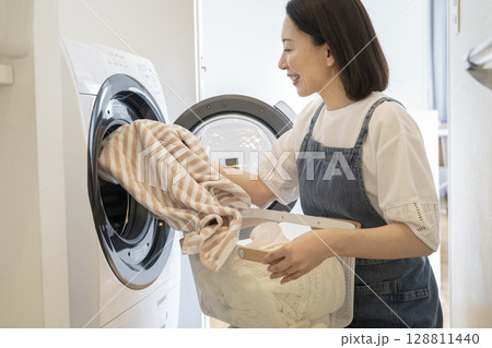 洗濯機に洗濯物を入れる50代の女性 洗濯機に洗濯物を入れる50代の女性 128811440