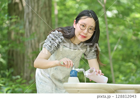 水筒に水を入れる若い女性 128812043