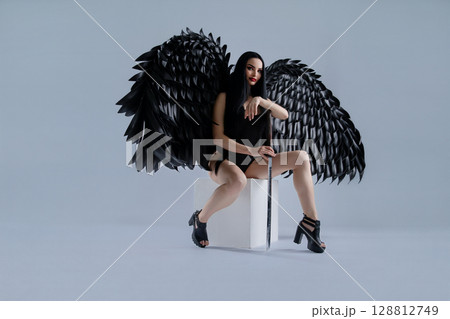 Stunning woman poses in seductive lingerie with striking black wings 128812749