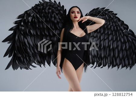 Elegant woman in lingerie with striking black wings posing confidently Elegant woman in lingerie with striking black wings posing confidently 128812754