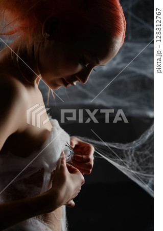 Red-haired woman trapped in a net, revealing her beauty amid the web Red-haired woman trapped in a net, revealing her beauty amid the web 128812767