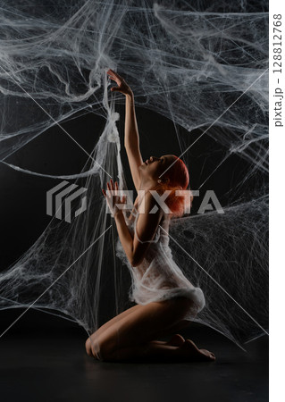 Red-haired woman entangled in a net trap resembling a spider web Red-haired woman entangled in a net trap resembling a spider web 128812768