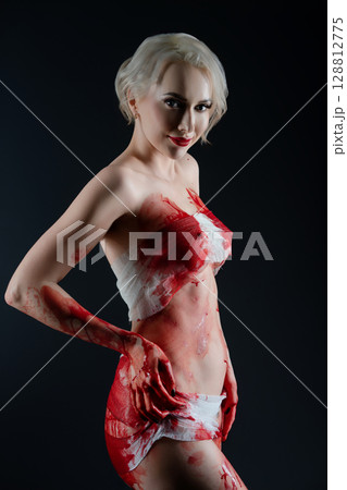 Naked woman poses dramatically with blood body art in a studio setting Naked woman poses dramatically with blood body art in a studio setting 128812775