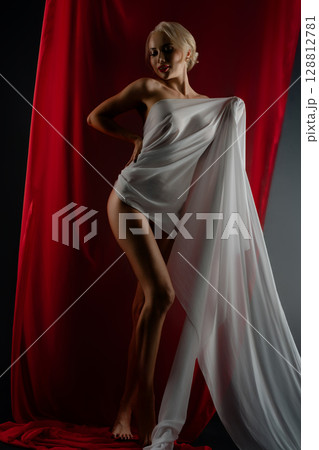 Elegant woman poses with flowing cloth in studio setting, dramatic lighting Elegant woman poses with flowing cloth in studio setting, dramatic lighting 128812781