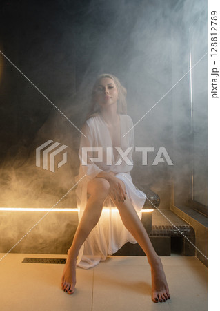 Relaxing moment for a woman in a spa sauna with soothing steam surrounding her 128812789