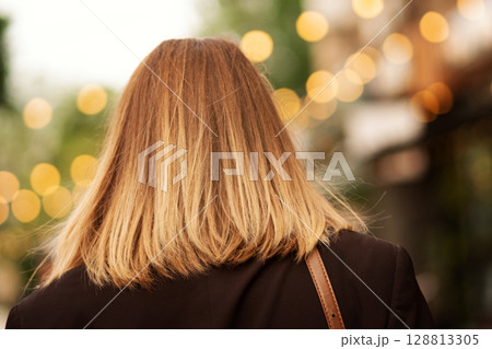 Back view of blonde woman with shoulder-length hair outdoors. Back view of blonde woman with shoulder-length hair outdoors. 128813305