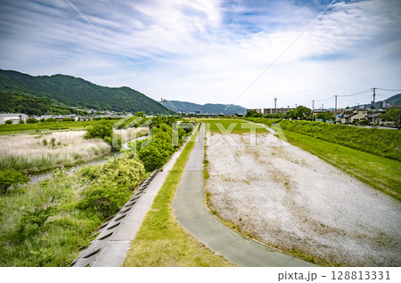 河川敷の遊歩道と草原が広がる夏の風景 河川敷の遊歩道と草原が広がる夏の風景 128813331