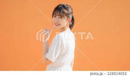 自然な笑顔のオレンジ背景での若い女性ポートレート 128814032