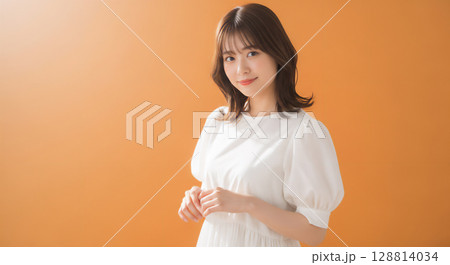 自然な笑顔のオレンジ背景での若い女性ポートレート 128814034
