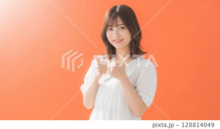 自然な笑顔のオレンジ背景での若い女性ポートレート 128814049