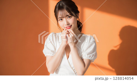 自然な笑顔のオレンジ背景での若い女性ポートレート 128814054
