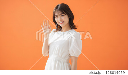 自然な笑顔のオレンジ背景での若い女性ポートレート 128814059