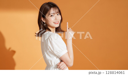 自然な笑顔のオレンジ背景での若い女性ポートレート 128814061