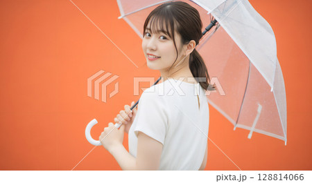 自然な笑顔のオレンジ背景での若い女性ポートレート 128814066