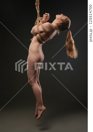 Woman suspended with shibari rope in a sensual bondage display Woman suspended with shibari rope in a sensual bondage display 128814700