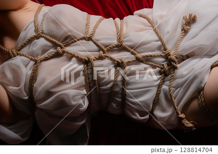 Shibari art featuring a woman in lingerie on a velvet backdrop Shibari art featuring a woman in lingerie on a velvet backdrop 128814704
