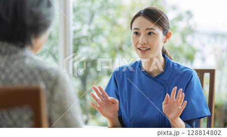 家族に説明する女性介護士 128814802