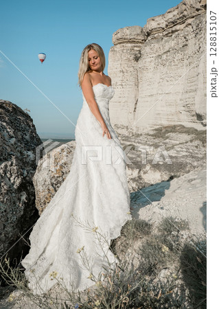 a woman in a white dress, a bride on a mountain with a blue sky. Beautiful nature, freedom, enjoyment of life. High quality photo 128815107