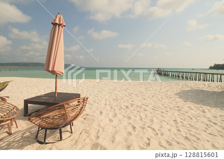 A solitary umbrella and wicker chairs facing the vast sea on a sunny summer day on the island of Koh Rong Sanloem, Sihanoukville, Cambodia A solitary umbrella and wicker chairs facing the vast sea on a sunny summer day on the island of Koh Rong Sanloem, Sihanoukville, Cambodia 128815601