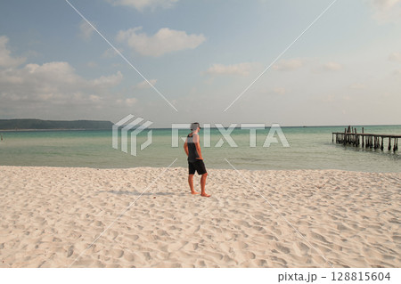 A man stands on a sandy beach looking out at the calm ocean in Koh Rong Sanloem, Sihanoukville, Cambodia A man stands on a sandy beach looking out at the calm ocean in Koh Rong Sanloem, Sihanoukville, Cambodia 128815604