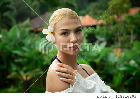 Woman poses elegantly in a lush tropical garden 128816203