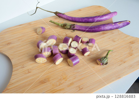 Sliced unusually shaped eggplant on wooden cutting board. Healthy food and vegetables. Organic seasonal farm products. 128816883
