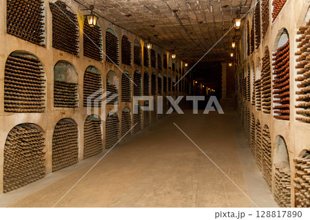 Ancient underground wine cellar with rows of aging bottles Ancient underground wine cellar with rows of aging bottles 128817890