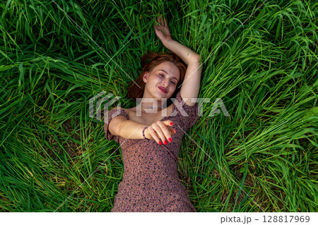Woman smiling while lying in tall green grass 128817969